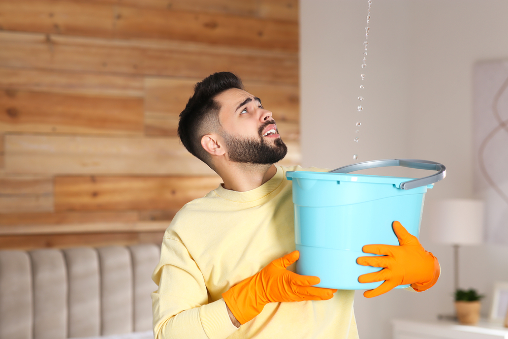 A man holding a bucket preventing water leak